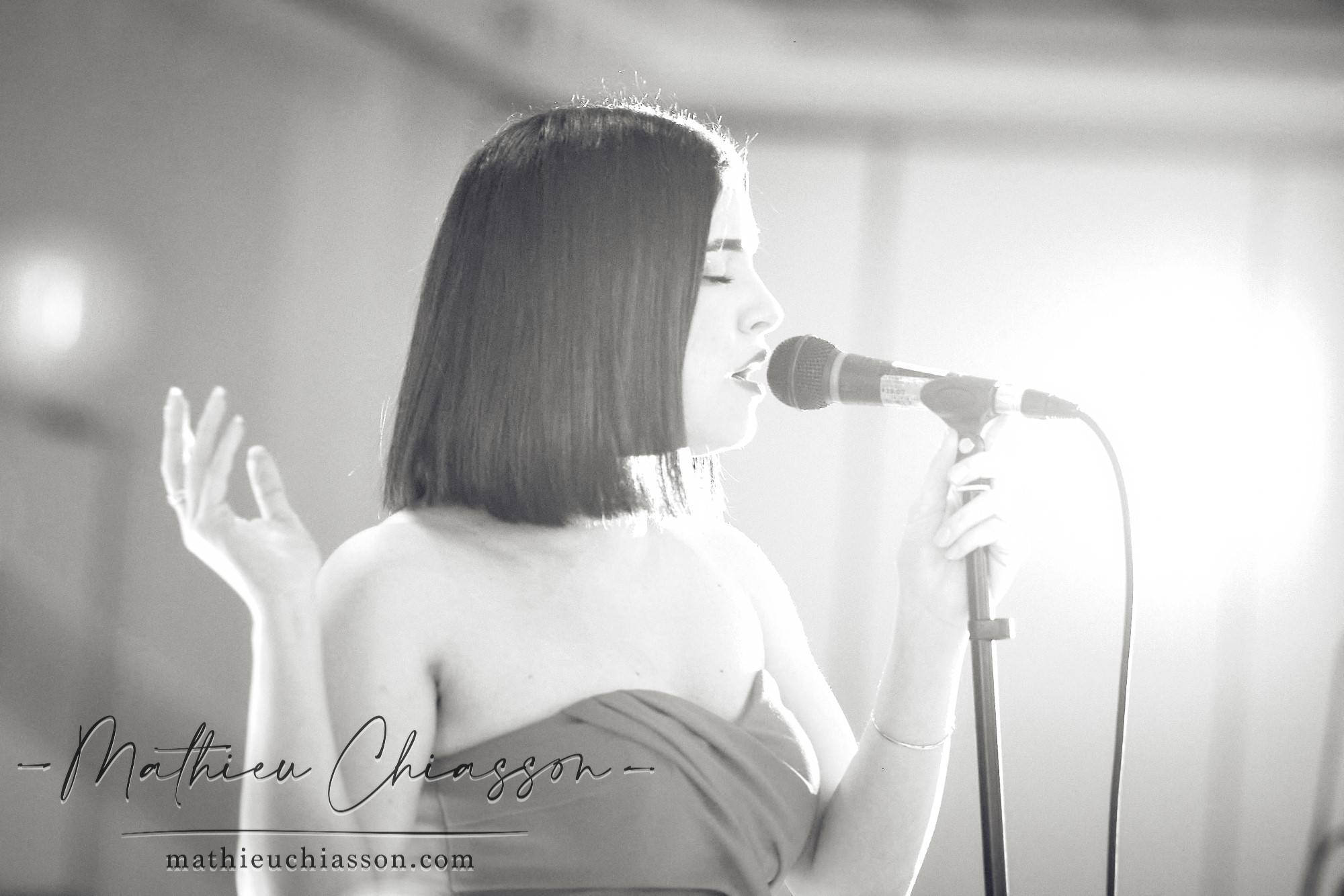 A singer performing at a microphone, photographed in black and white.