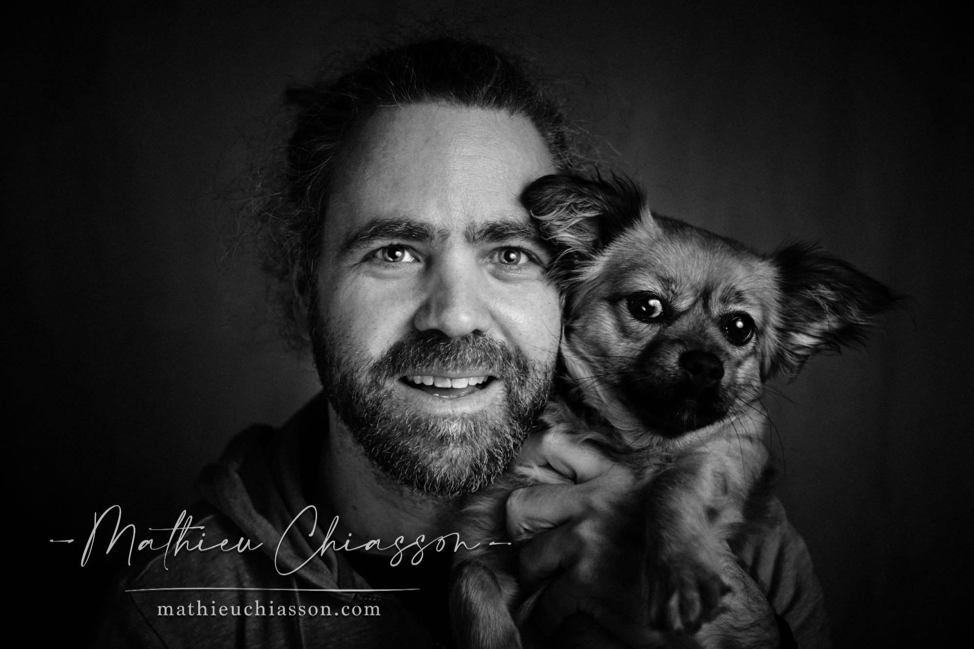 A black-and-white portrait of a man holding a small dog.